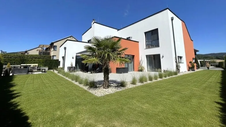 Modernes Einfamilienhaus mit gepflegtem Garten, Rasenfläche und einer Terrasse für entspannte Stunden im Freien.