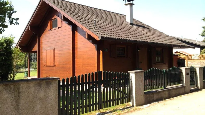 Charmantes Holzhaus mit Satteldach und gepflegtem Vorgarten, umgeben von einem Holzzaun.