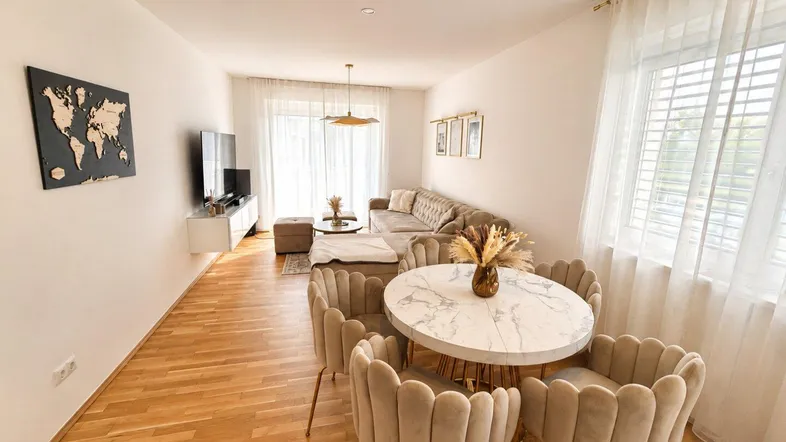 Helles Wohn- und Esszimmer mit Parkettboden, modernem Mobiliar und dekorativer Wandkarte.