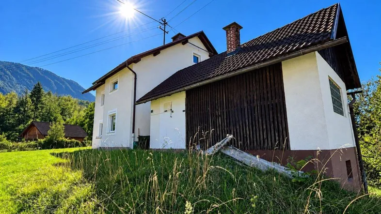 Ländliches Haus mit weißer Fassade, Holzelementen und Blick auf die umliegende Berglandschaft.