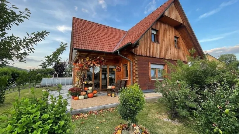 Gemütliche Terrasse mit herbstlicher Dekoration und Blick auf das Holzhaus.