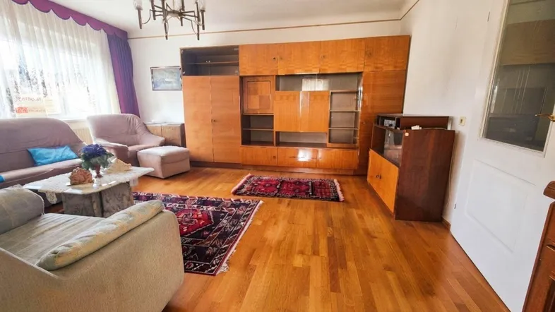 Geräumiges Wohnzimmer mit Holzparkettboden, großer Schrankwand und gemütlichen Sofas.