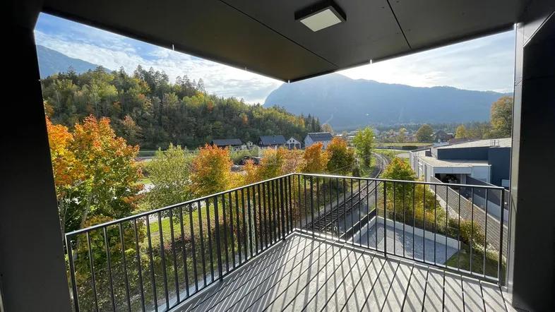 Geräumiger Balkon mit Holzboden und atemberaubendem Blick auf die umliegende Berglandschaft und Herbstbäume.