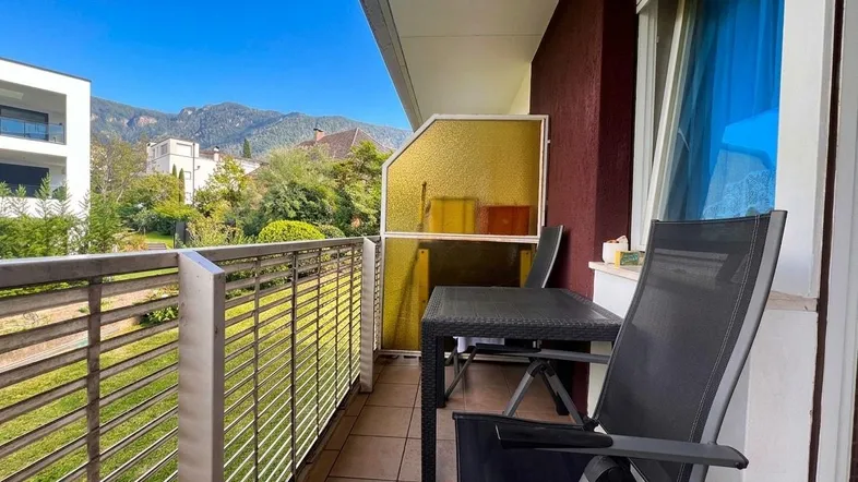 Sonniger Balkon mit Bergblick, gefliestem Boden und Sitzgelegenheiten im Freien.