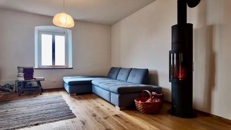 Gemütliches Wohnzimmer mit modernem Kaminofen, bequemer Couch und Holzboden.