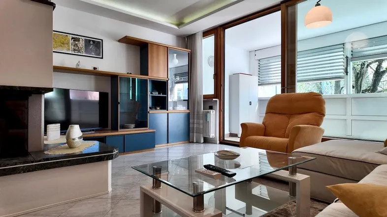Gemütliches Wohnzimmer mit Kamin, TV-Möbeln und Zugang zu einem Balkon.