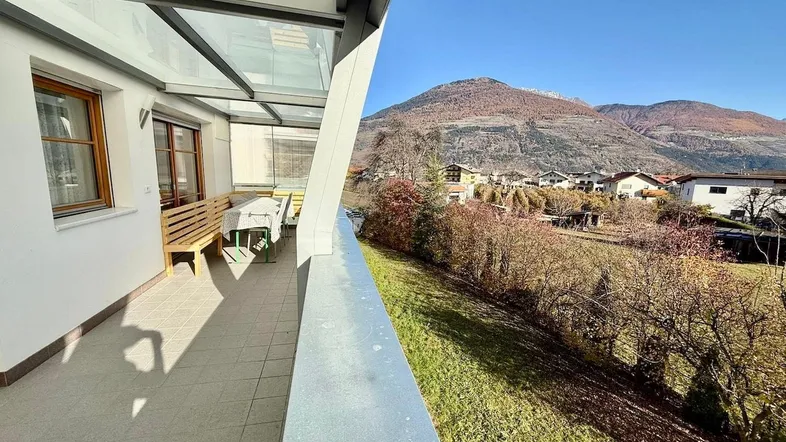 Überdachte Terrasse mit Sitzgelegenheiten und weitem Blick auf die umliegende Berglandschaft.