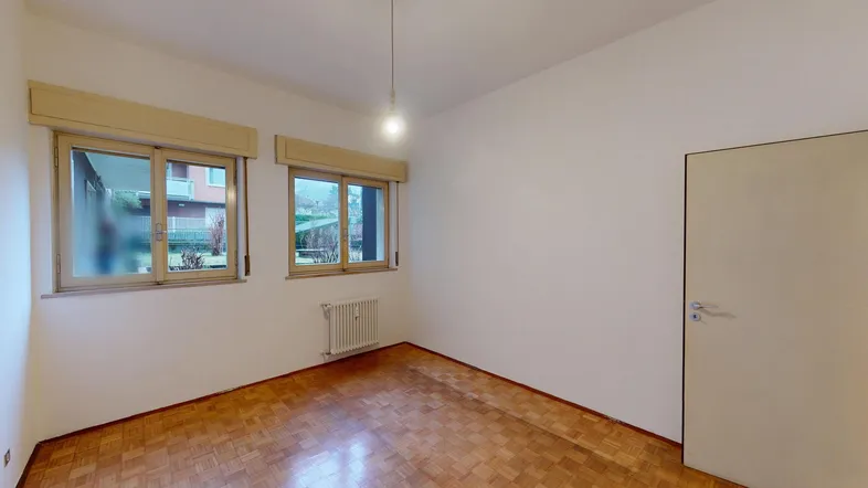 Helles Zimmer mit Parkettboden und zwei Fenstern, ideal als Schlafzimmer nutzbar.