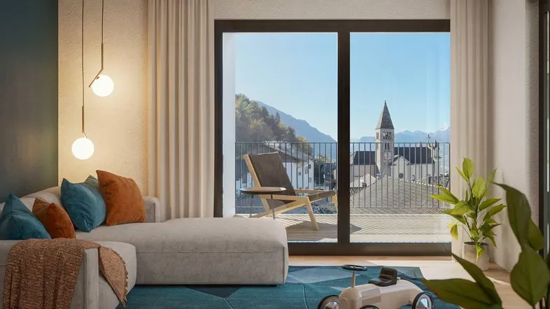 Helles Wohnzimmer mit gemütlichem Sofa, modernem Teppich und Zugang zu einem Balkon mit Bergblick.