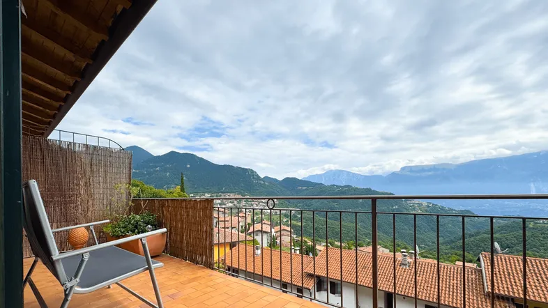 Geräumiger Balkon mit Terrakottaboden, Sitzgelegenheit und weitem Blick auf die umliegende Berglandschaft.