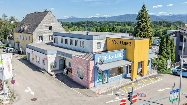 Luftaufnahme eines Geschäftsgebäudes mit farbenfrohen Fassaden und einem angrenzenden Wohnhaus.