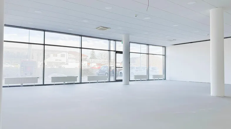 Heller, leerer Gewerberaum mit großen Fenstern und Säulen, bereit für den Ausbau.