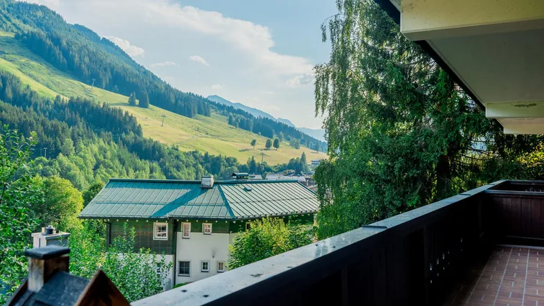Geräumiger Balkon mit Holzboden und atemberaubendem Blick auf die umliegenden Berge und grüne Täler.