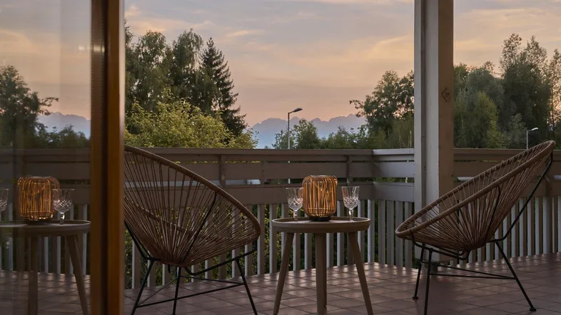 Gemütlicher Balkon mit Korbsesseln und Laternen, ideal für entspannte Abende im Freien.