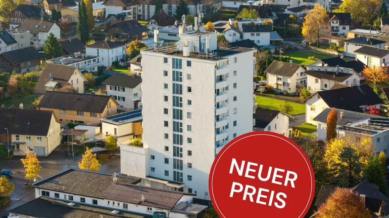 Luftaufnahme eines Hochhauses in einer Wohnsiedlung mit Herbstbäumen und umliegenden Häusern.