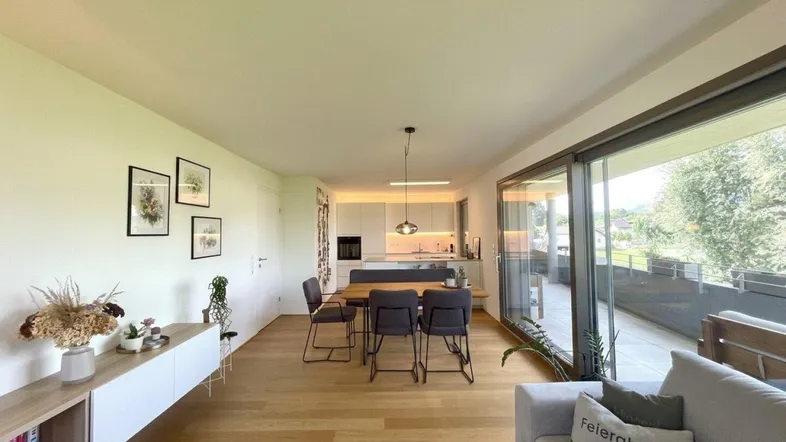 Helles, offenes Wohn-Esszimmer mit Holzboden, moderner Küche und Zugang zur Terrasse.