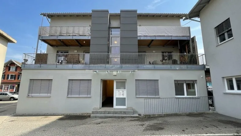 Modernes Mehrfamilienhaus mit Balkonen und Rampe für barrierefreien Zugang.