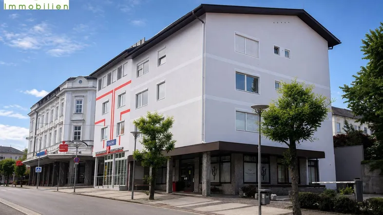 Gebäudeansicht von der Straße mit mehreren Stockwerken und Geschäftsflächen im Erdgeschoss.