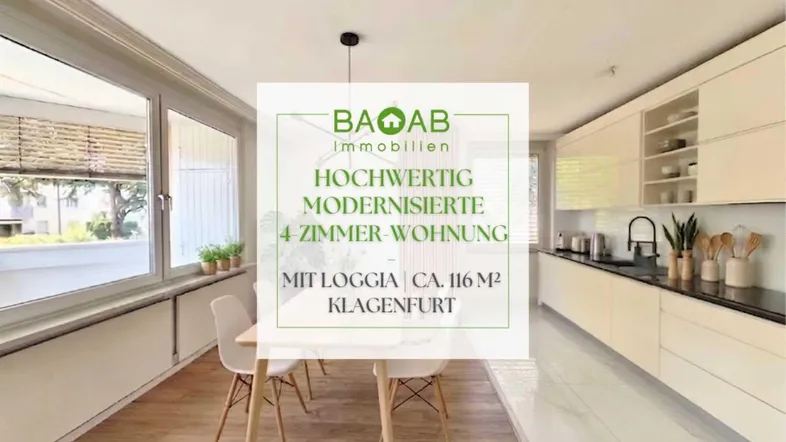Moderne Küche mit Essbereich, hellen Schränken, dunkler Arbeitsplatte und großem Fenster.
