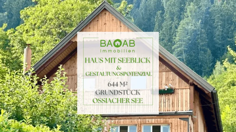 Rustikales Holzhaus mit Giebeldach, umgeben von grünen Bäumen und Bergen im Hintergrund.