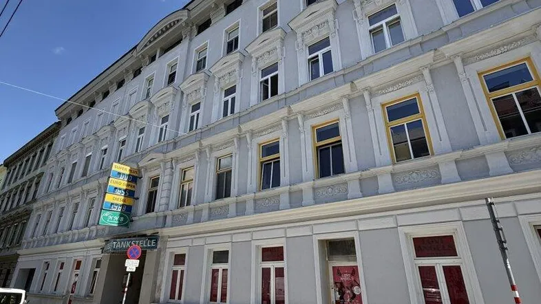 Historisches Mehrfamilienhaus mit klassischer Fassade und vielen Fenstern an einer Straße.