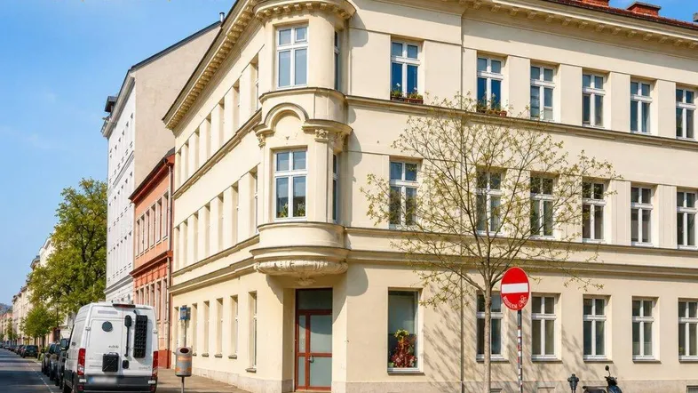 Klassisches Eckgebäude mit eleganter Fassade und vielen Fenstern an einer städtischen Straße.