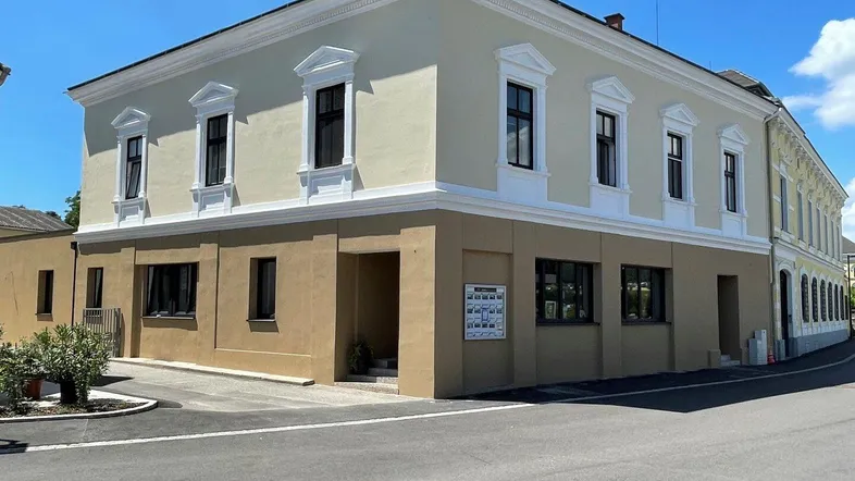 Klassisches Gebäude mit frisch gestrichener Fassade und dekorativen Fensterrahmen.