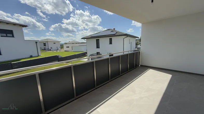 Geräumiger Balkon mit moderner Brüstung und Blick auf die umliegenden Neubauten.