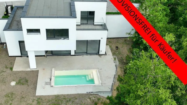 Moderne weiße Villa mit Flachdach und kleinem Pool, umgeben von viel Grün.