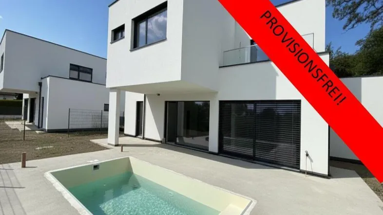Modernes weißes Haus mit kleinem Pool und minimalistischer Architektur, umgeben von einer gepflasterten Terrasse.