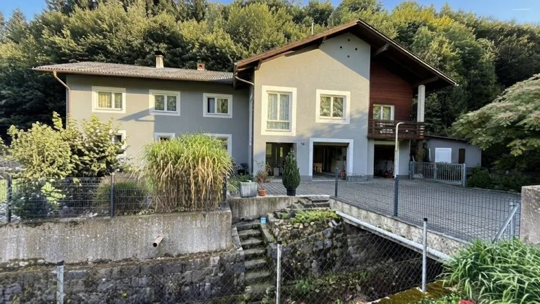 Großzügiges Einfamilienhaus umgeben von viel Grün und Bäumen in ländlicher Umgebung.