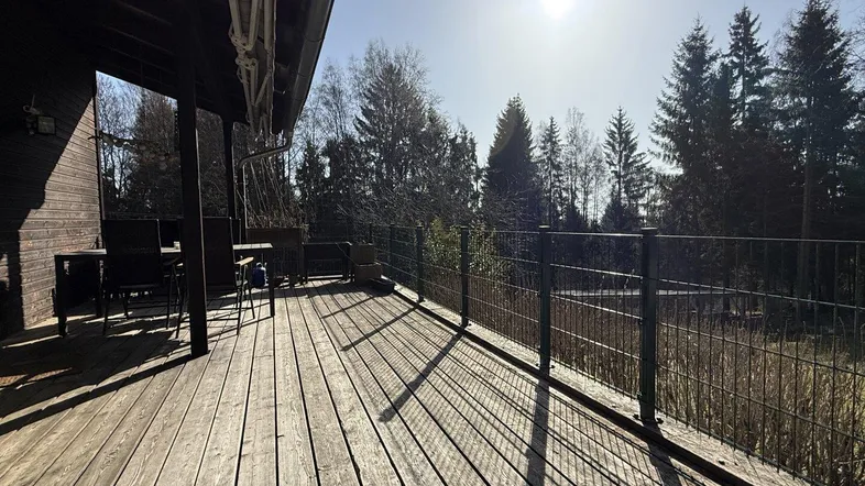 Geräumige Holzterrasse mit Blick auf den umliegenden Wald und viel Sonnenlicht.