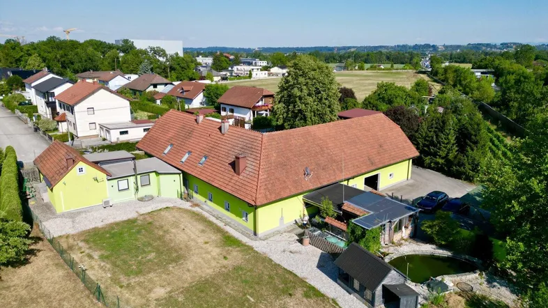Luftaufnahme des Anwesens mit Teich, Hauptgebäude und umliegender Wohnbebauung sowie Feldern.