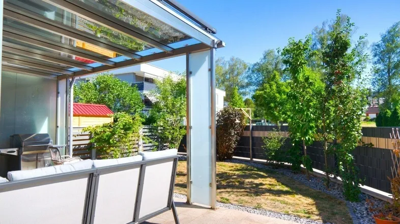 Überdachte Terrasse mit Gartenmöbeln und Blick ins Grüne, ideal für entspannte Stunden im Freien.