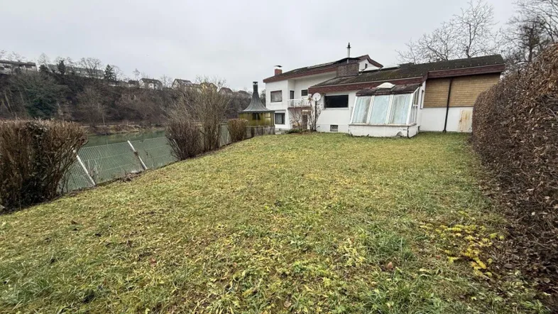 Großer Gartenbereich mit Rasenfläche und Blick auf das Wohnhaus sowie die umliegende Landschaft.