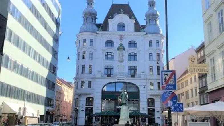 Historisches Gebäude mit markanter Architektur und umliegender Stadtansicht in einer belebten Straße.
