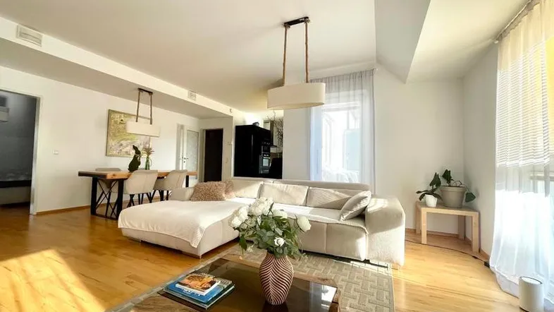 Helles, offenes Wohn- und Esszimmer mit Parkettboden und modernem Sofa.