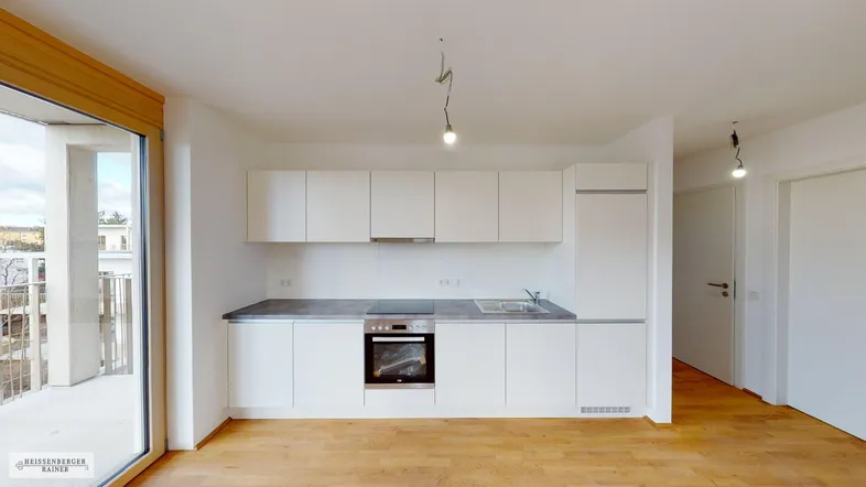 Moderne, helle Einbauküche mit weißen Fronten, integrierten Geräten und Holzboden.