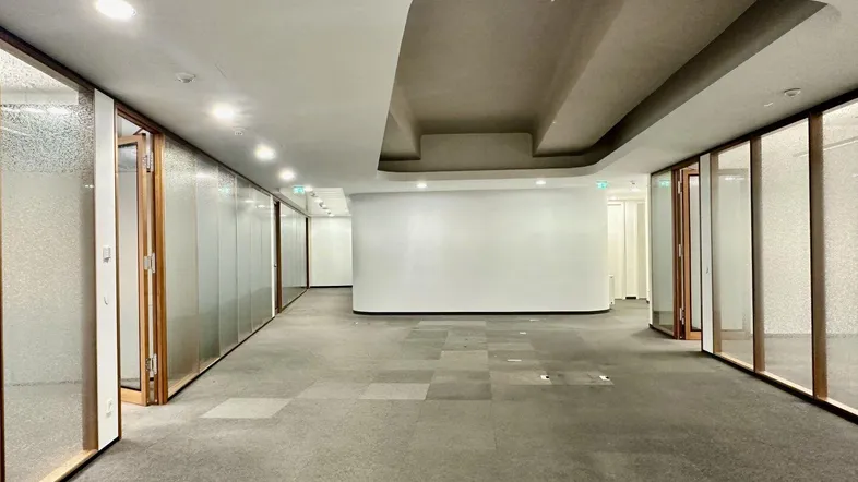 Geräumiger Bürobereich mit modernen Glaswänden und Teppichboden, ideal für flexible Arbeitsplatzgestaltung.