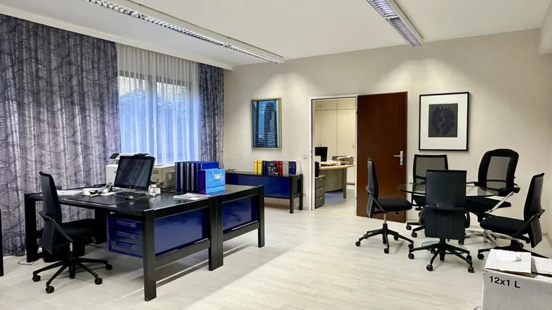 Geräumiges Büro mit mehreren Arbeitsplätzen, blauen Akzenten und hellen Böden.