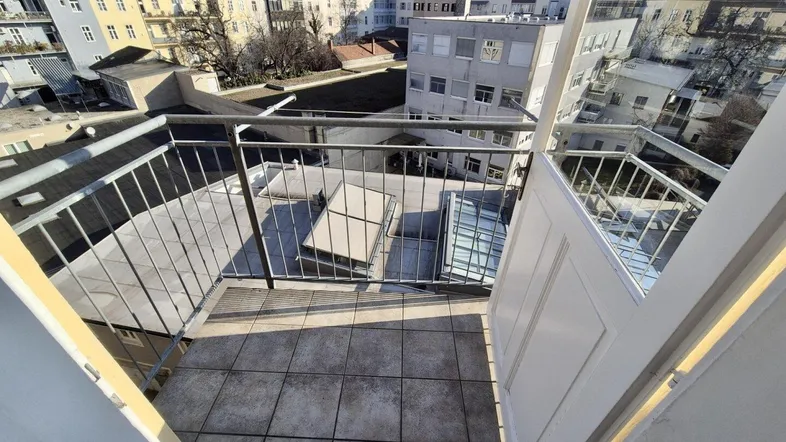 Kleiner Balkon mit Fliesenboden und Blick auf die umliegenden Gebäude der Stadt.