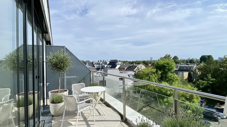 Große Dachterrasse mit Sitzgelegenheiten, Pflanzen und weitem Stadtblick unter blauem Himmel.