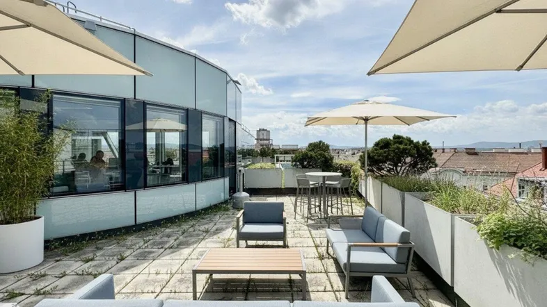 Geräumige Dachterrasse mit modernen Loungemöbeln, Sonnenschirmen und weitem Stadtblick.