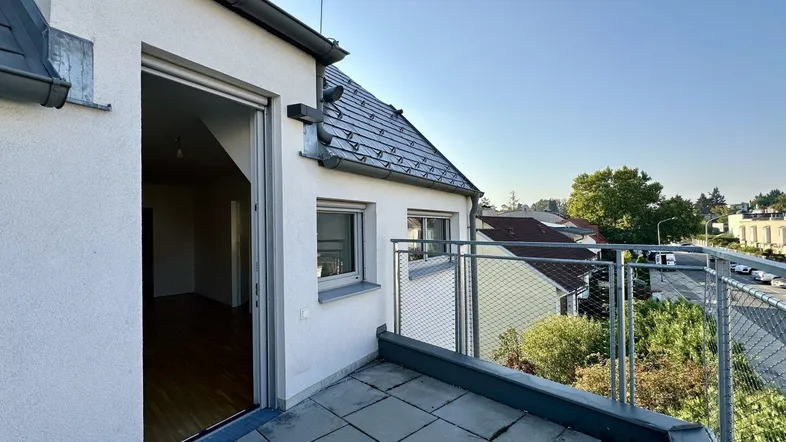 Geräumiger Balkon mit Fliesenboden und Blick auf die umliegende Wohngegend und viel Grün.
