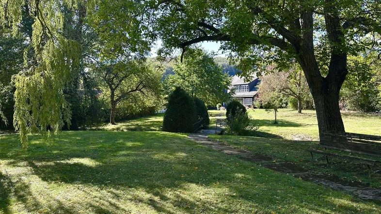 Großer, gepflegter Garten mit altem Baumbestand und Blick auf das charmante Landhaus im Hintergrund.