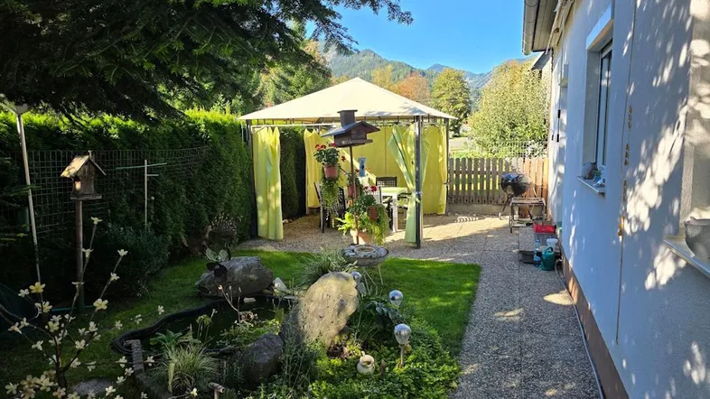 Gepflegter Gartenbereich mit Pavillon, Teich und Bergblick, ideal für entspannte Stunden im Freien.