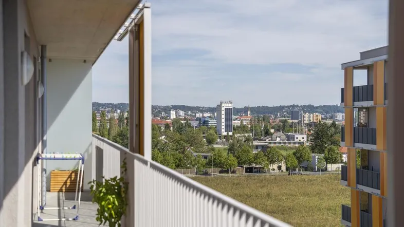 Geräumiger Balkon mit weitem Blick über die Stadt und grüne Hügel in der Ferne.
