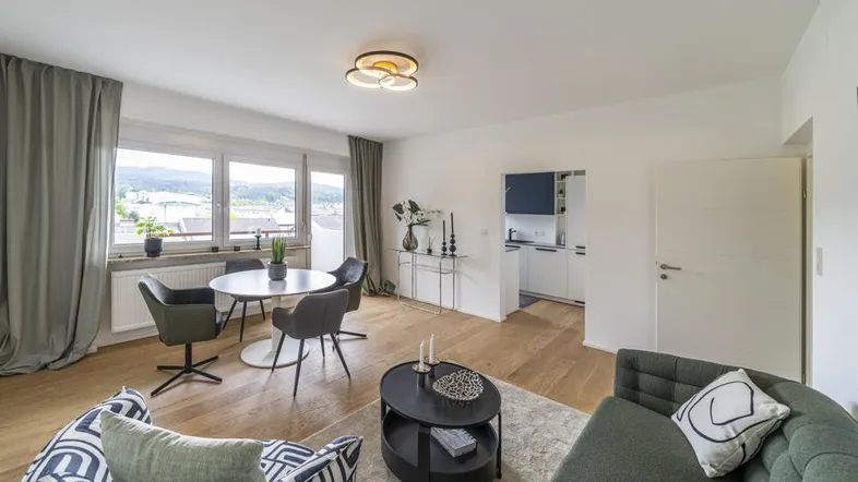 Heller Wohn- und Essbereich mit Holzboden, modernen Möbeln und Blick auf die Landschaft.