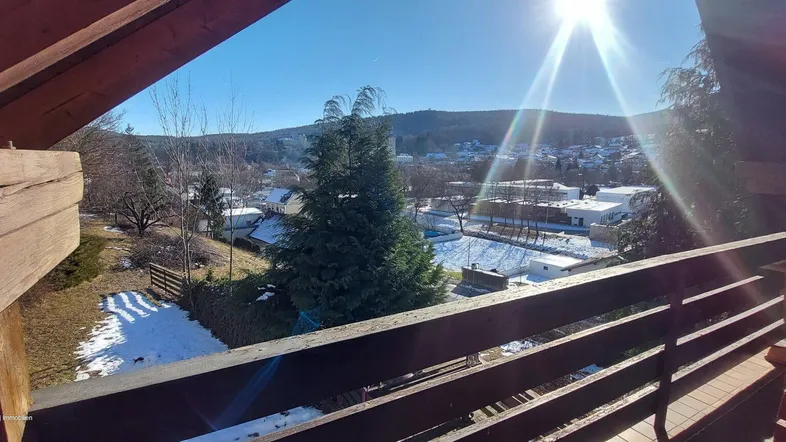 Sonnige Aussicht vom Balkon mit Blick auf die verschneite Landschaft und die umliegenden Häuser.