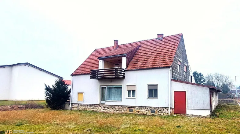 Einfamilienhaus mit Satteldach, Balkon und großem Grundstück in ländlicher Umgebung.